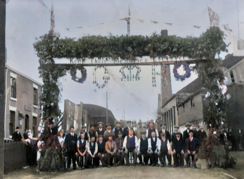 Colourised photograph of the Marston EverGreen Remembrance Arch and villagers, circa 1918.