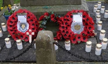 Poppy wreaths and remembrance candles at the base of the Marston War Memorial.