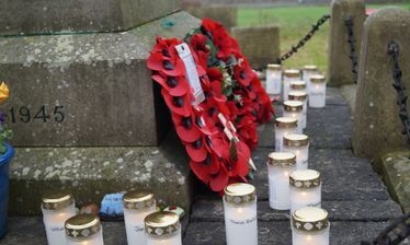 A poppy wreath and candles beside the names on the Marston War Memorial.