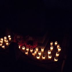A circle of illuminated remembrance candles at night.