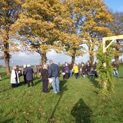 People gathered beneath an autumn tree at the Marston remembrance service.