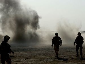 Soldiers silhouetted against smoke and an explosion.