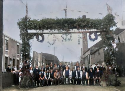 Colourised photograph of villagers beneath the Marston EverGreen Remembrance Arch.