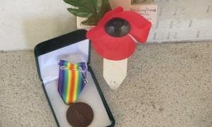 John Johnson's medal displayed with a poppy and remembrance cross.